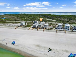 En fastighet vid stranden med flera byggnader, en sandstrand och fri utsikt över havet.