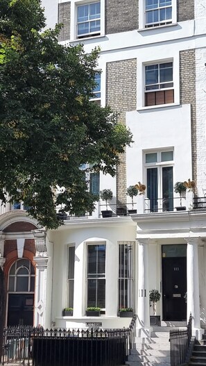 Un immeuble à plusieurs étages, doté d’une façade blanche, de nombreuses fenêtres et d’une porte noire portant le numéro 111.