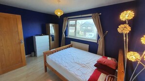 A bedroom with a bed, a wardrobe, a dresser, and a window with curtains. - Detached 4-bed House in Leeds (Leeds)