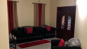 A living room with a black sofa, a red rug, and a ceiling fan. - Lapiz Lazuli at Serenity Palms (Runaway Bay)
