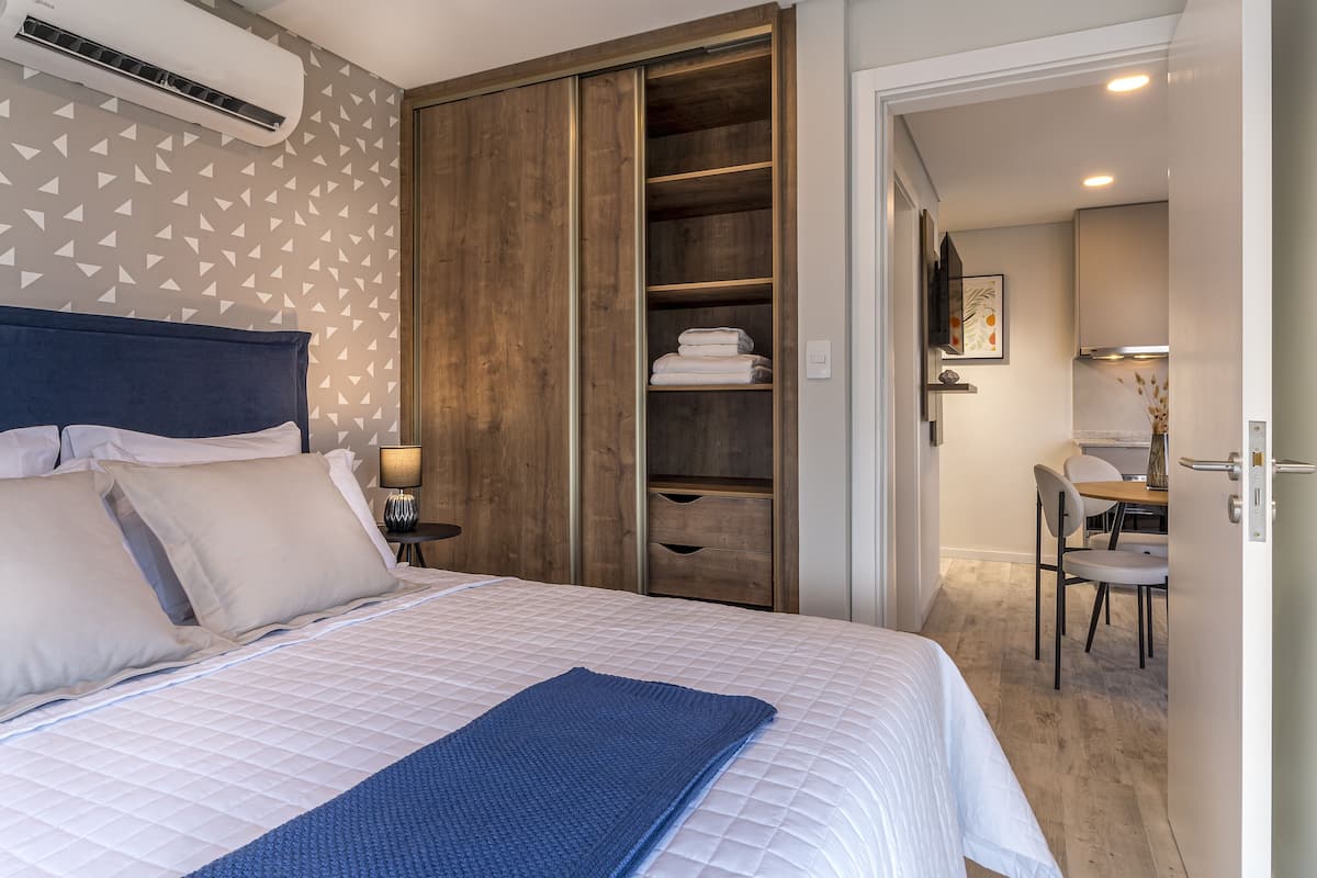 A hotel room with a bed, a wardrobe, a desk, and a chair.