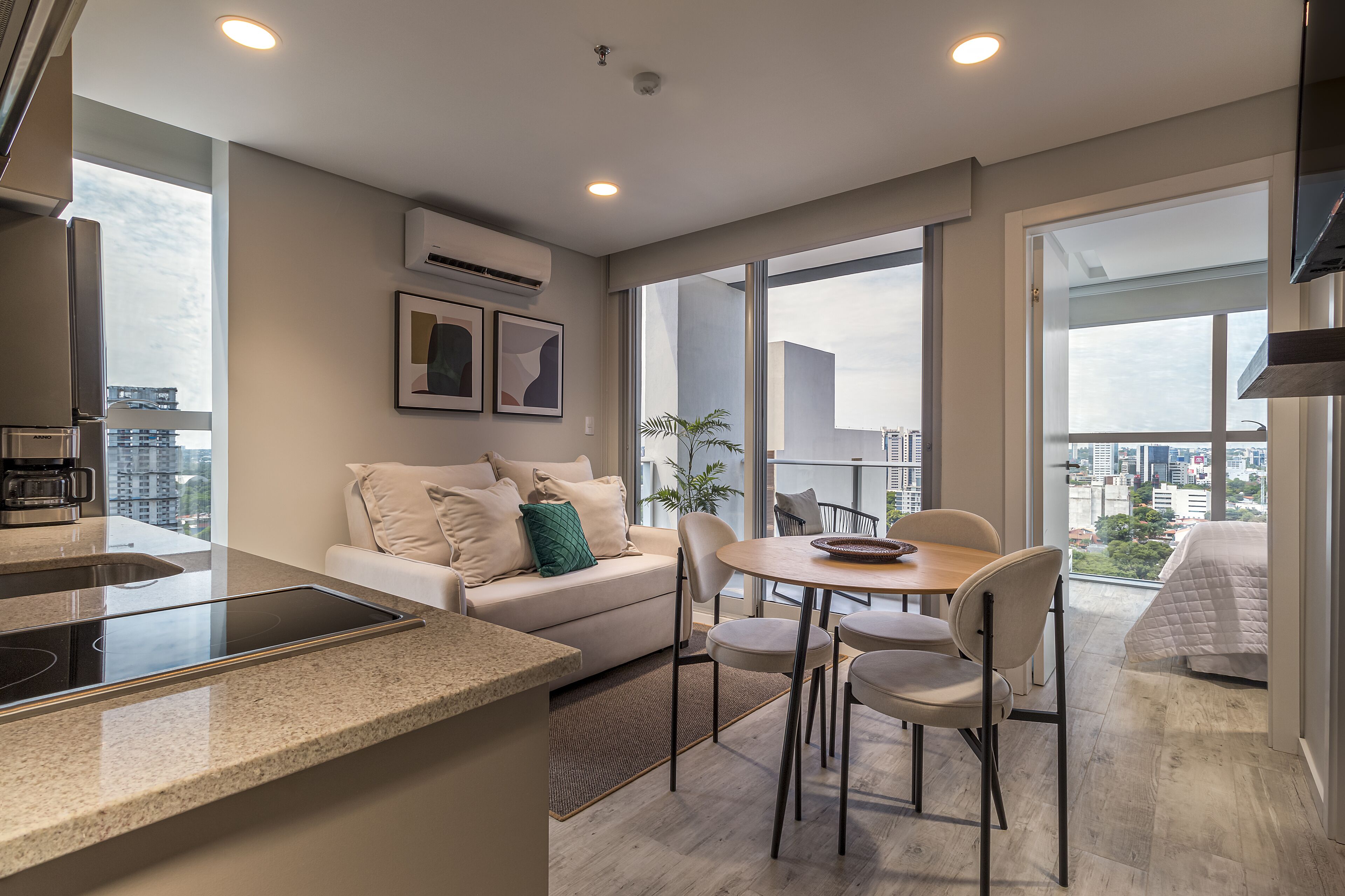 Eine moderne Wohnung mit Küche, Essbereich und einem Balkon mit Blick auf die Stadt.