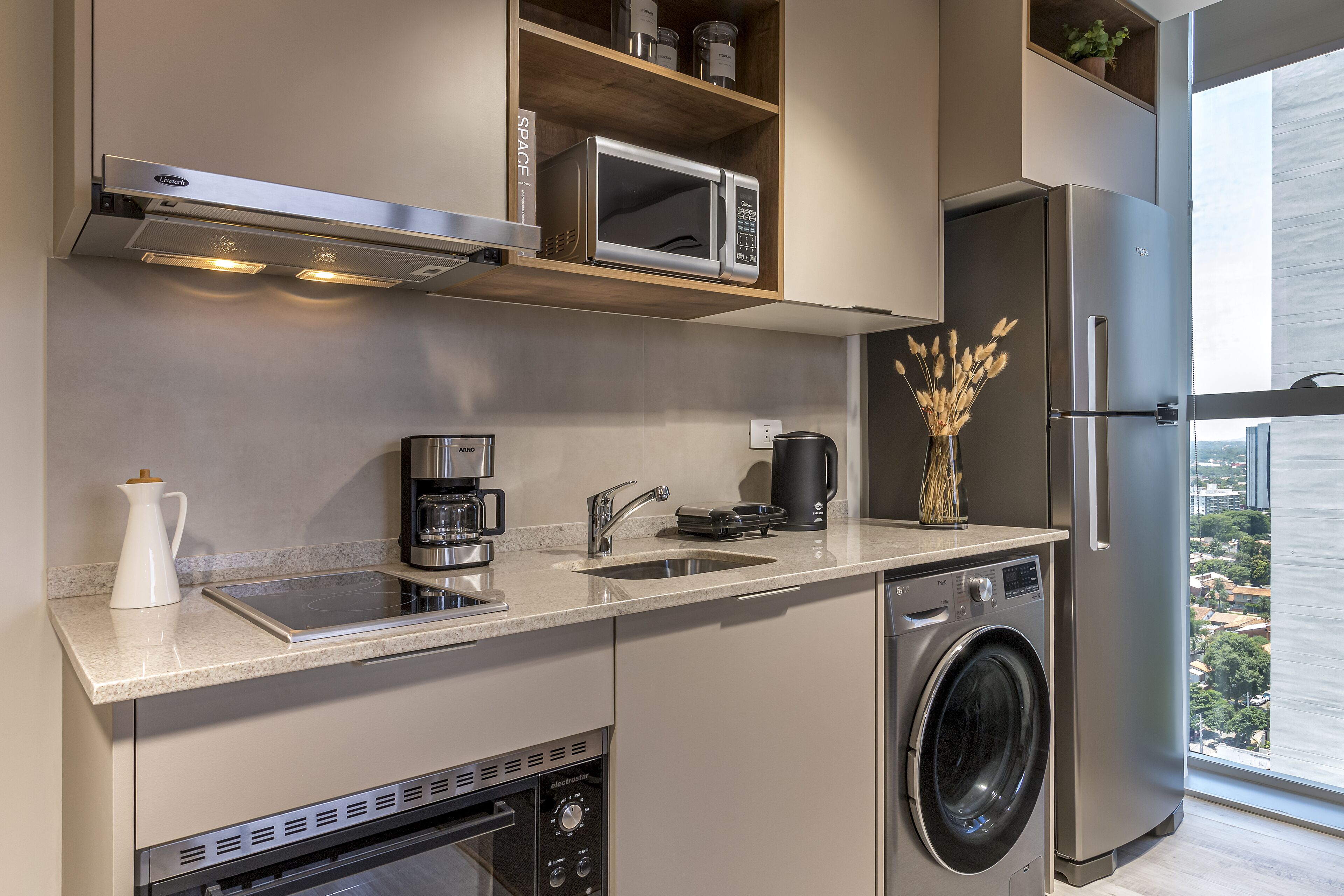 A compact kitchen with a built-in microwave, coffee maker, and washing machine.