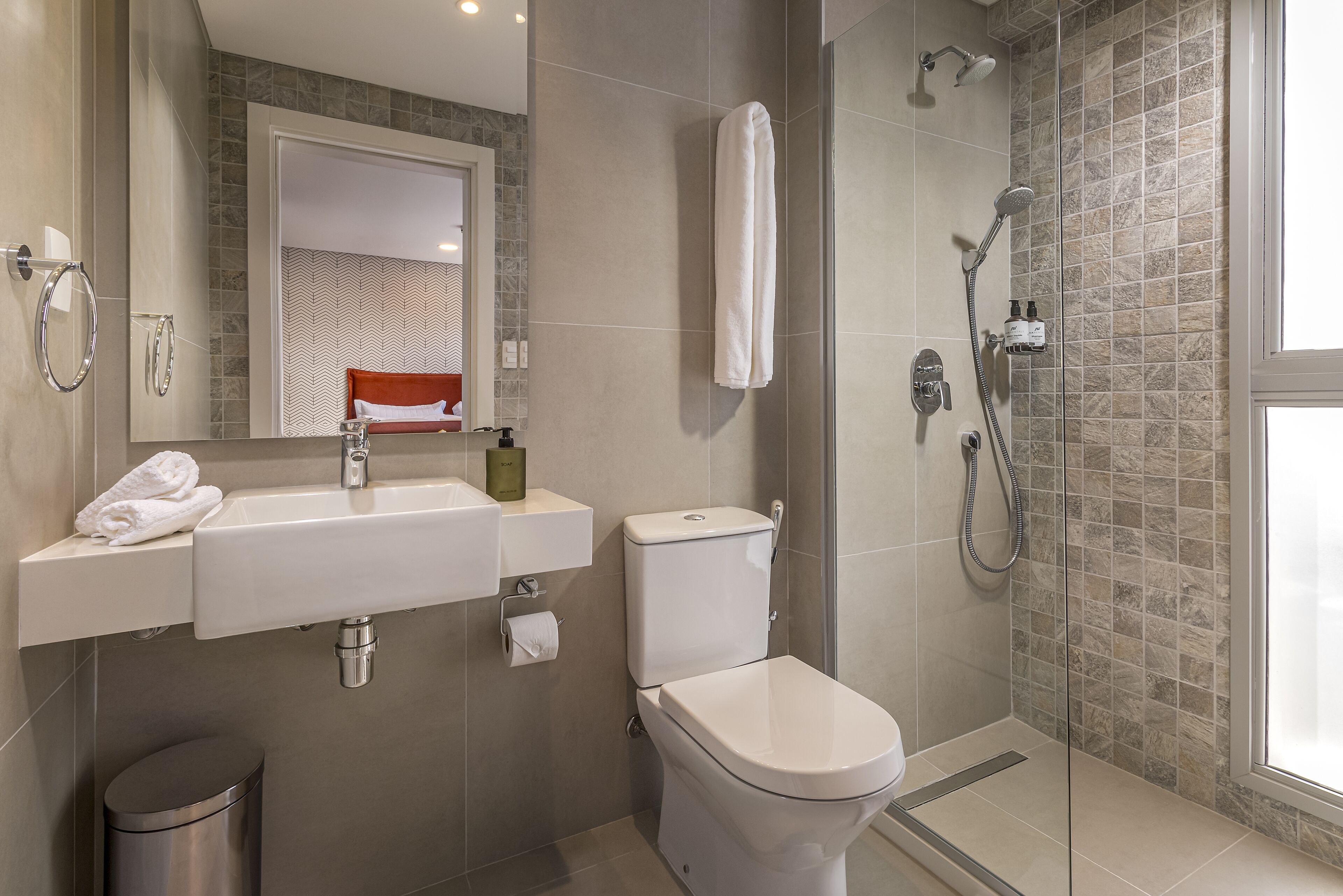Un baño moderno con lavamanos, inodoro y ducha.