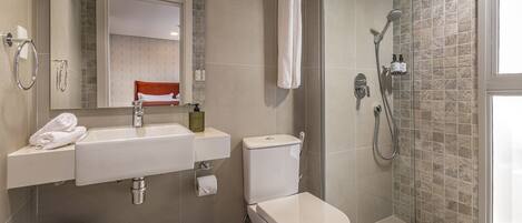 Un baño moderno con lavamanos, inodoro y ducha.