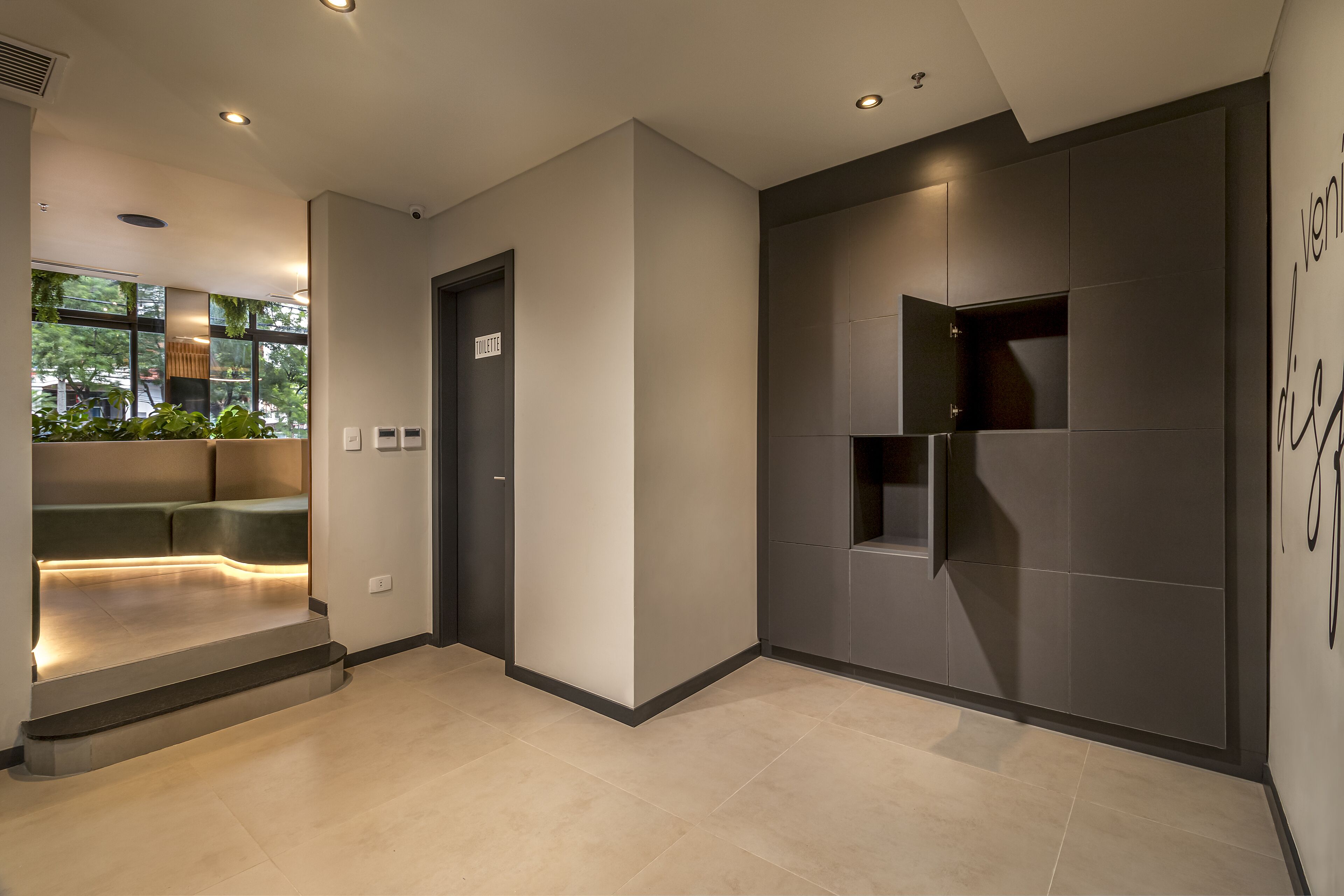 A modern hotel lobby with a seating area, a door, and a wall with a built-in shelf.