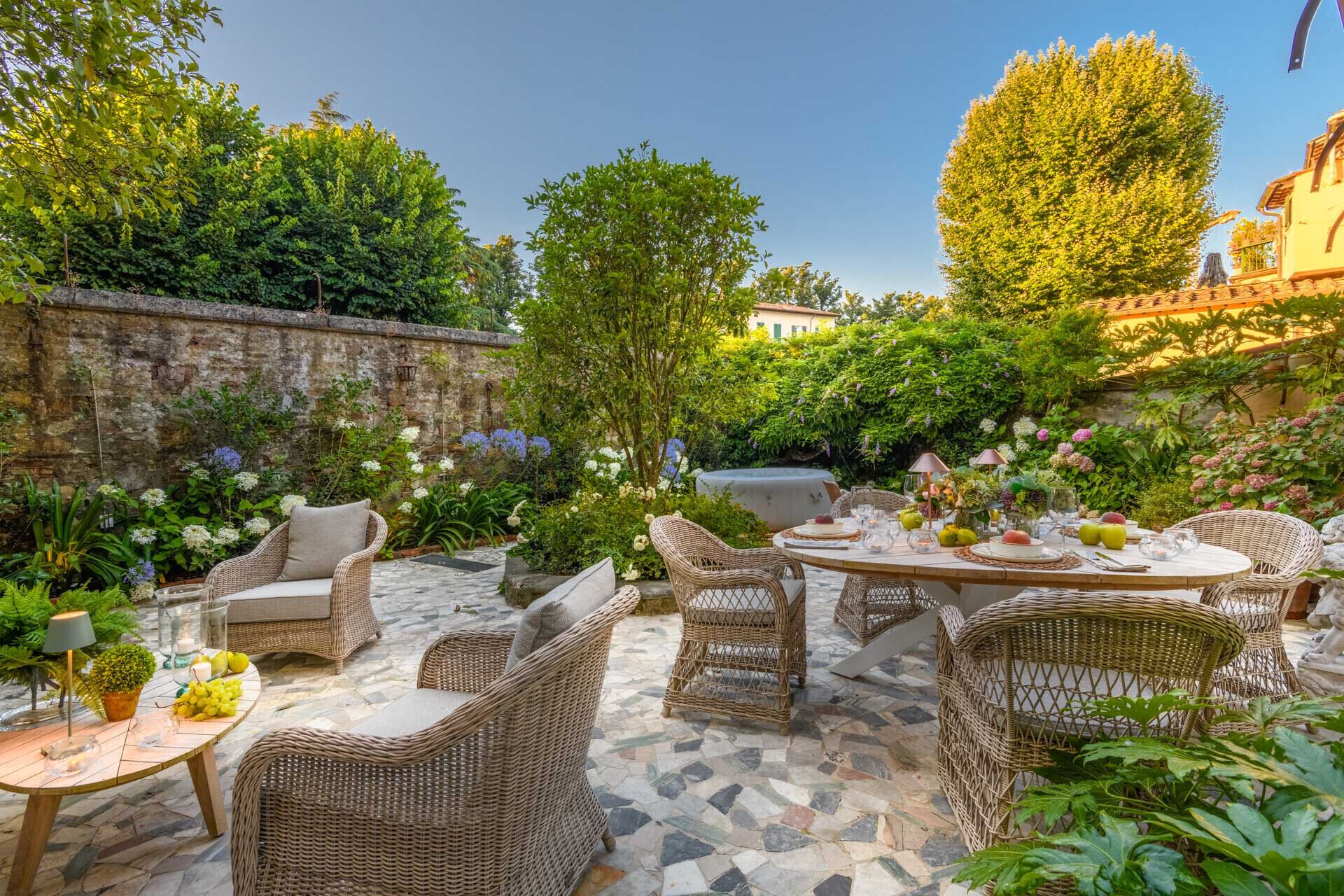 A patio with wicker furniture, a round table, and a stone wall.