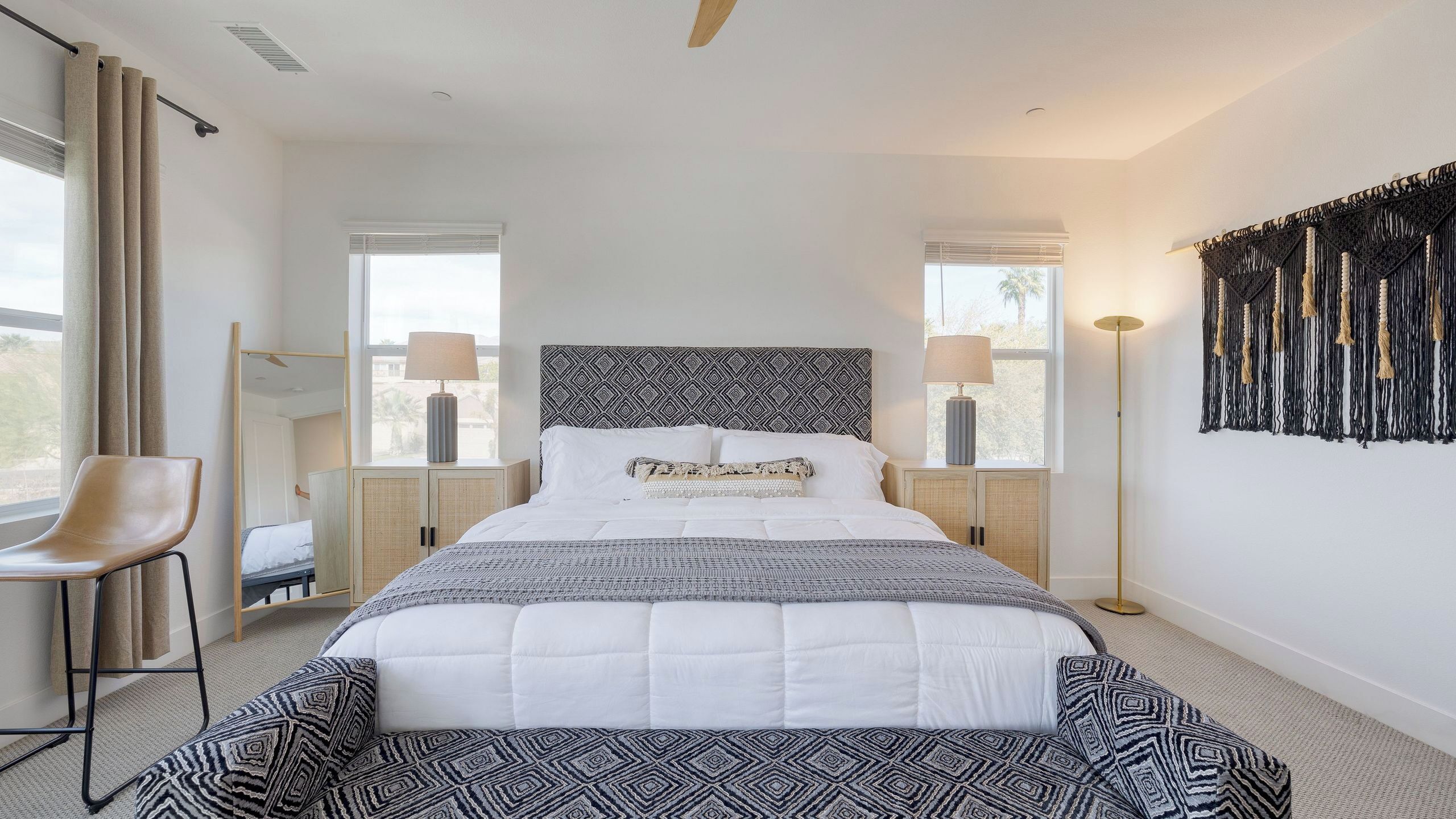 A modern bedroom with a large bed, two bedside tables with lamps, a chair, and a floor lamp.