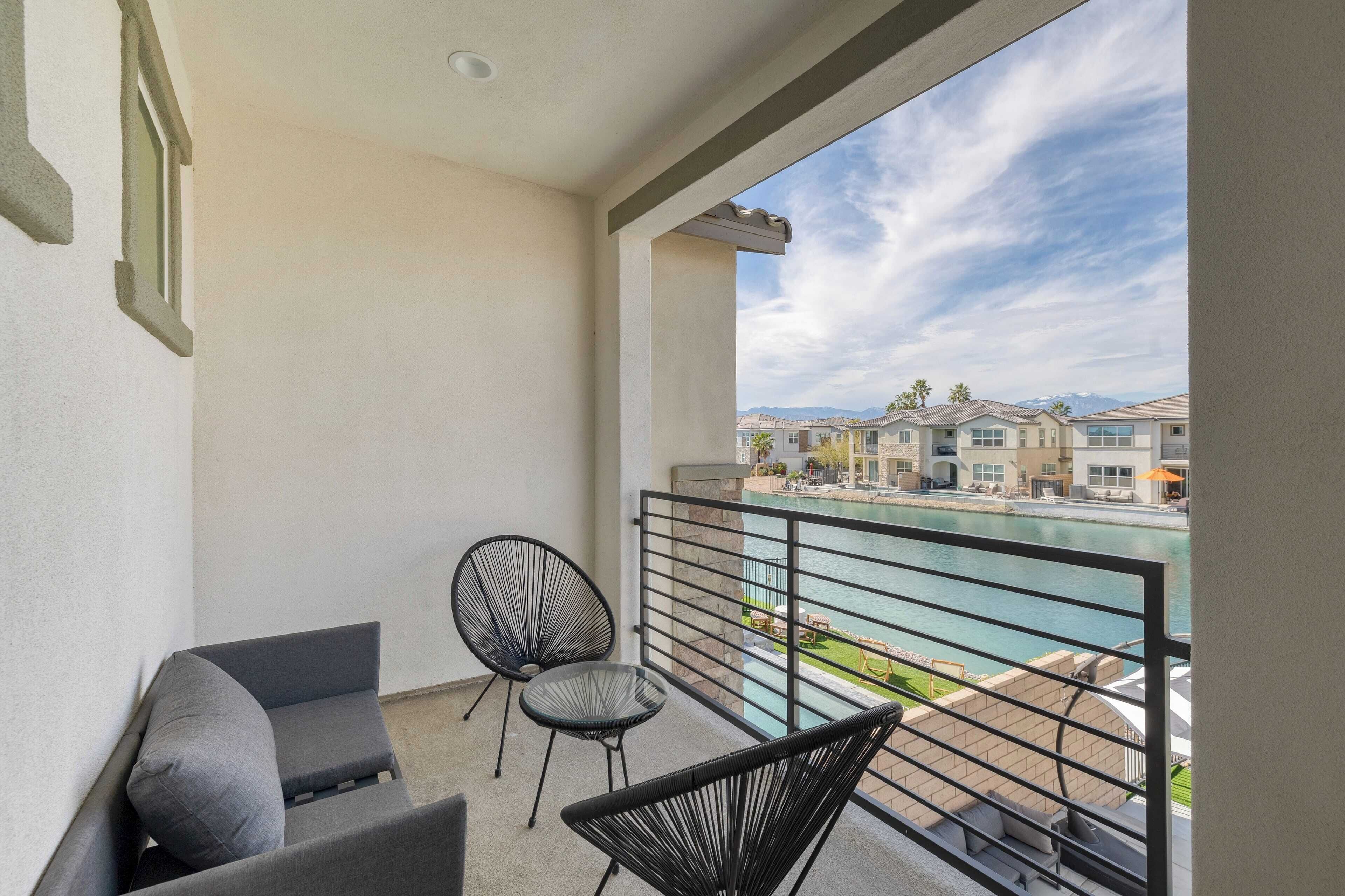 Un balcón con vista a la piscina, dos sillones y un sofá.