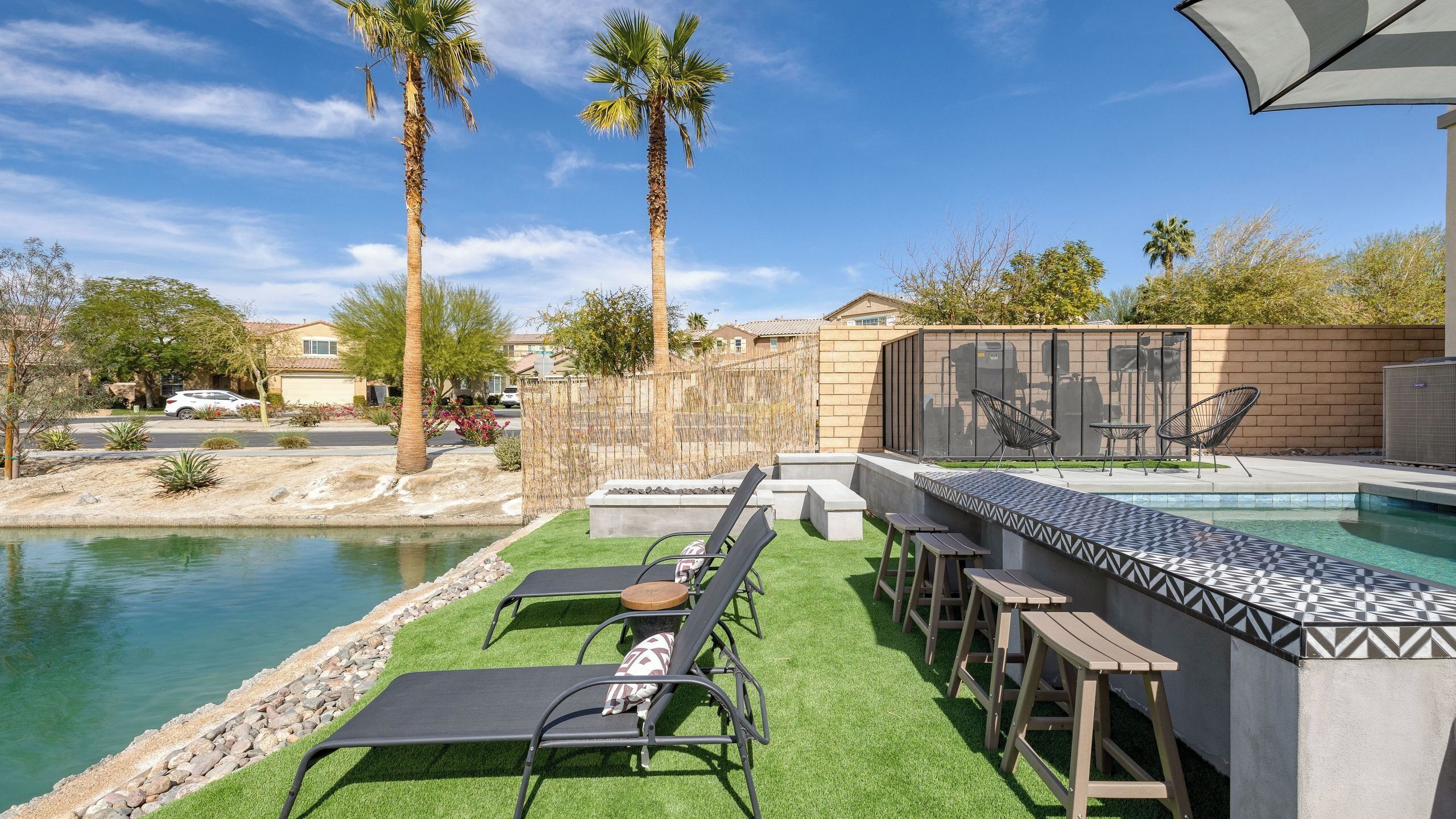 A poolside area with lounge chairs, a barbecue grill, and a view of the pool.