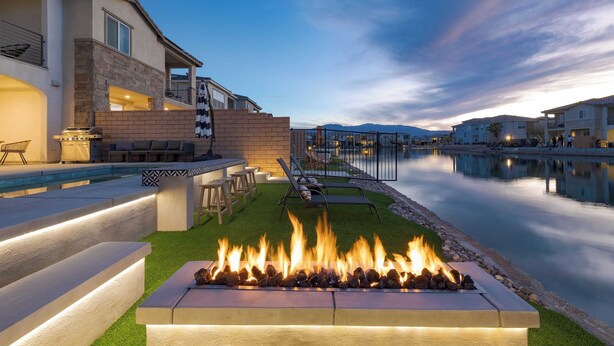 A poolside area with a fire feature, outdoor seating, and a view of the water.