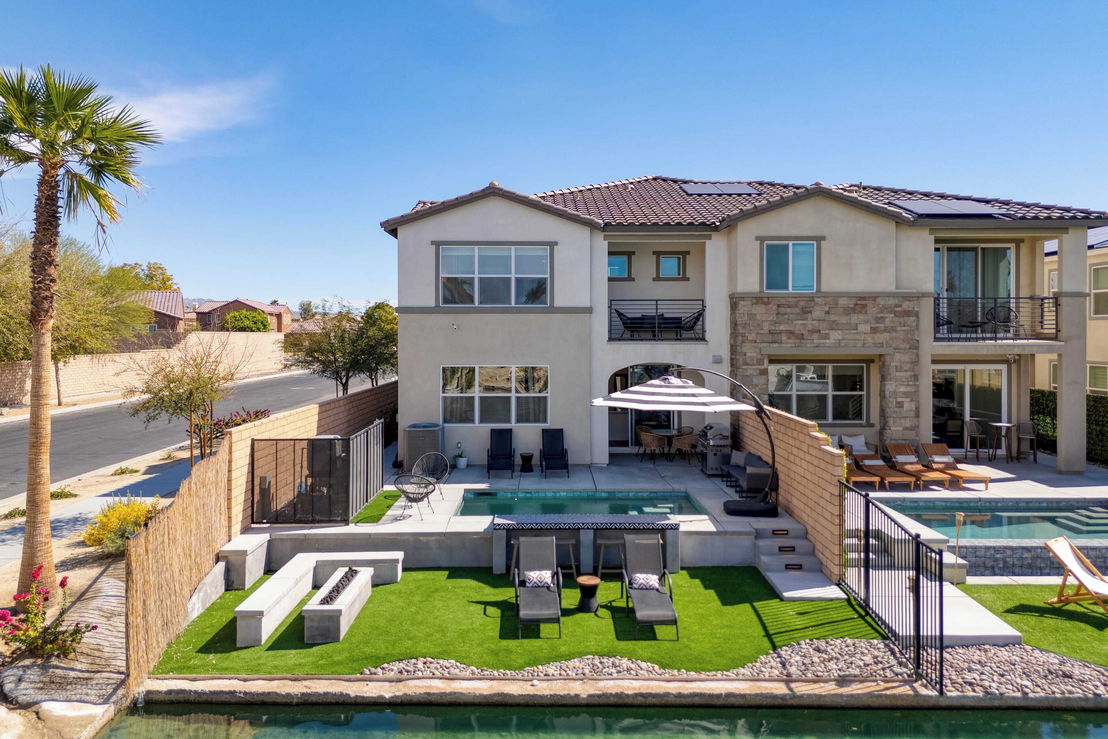 Une maison à deux étages avec une piscine, un espace extérieur aménagé et une pelouse bien entretenue.