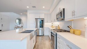 A modern kitchen with white cabinetry, stainless steel appliances, and a central island.