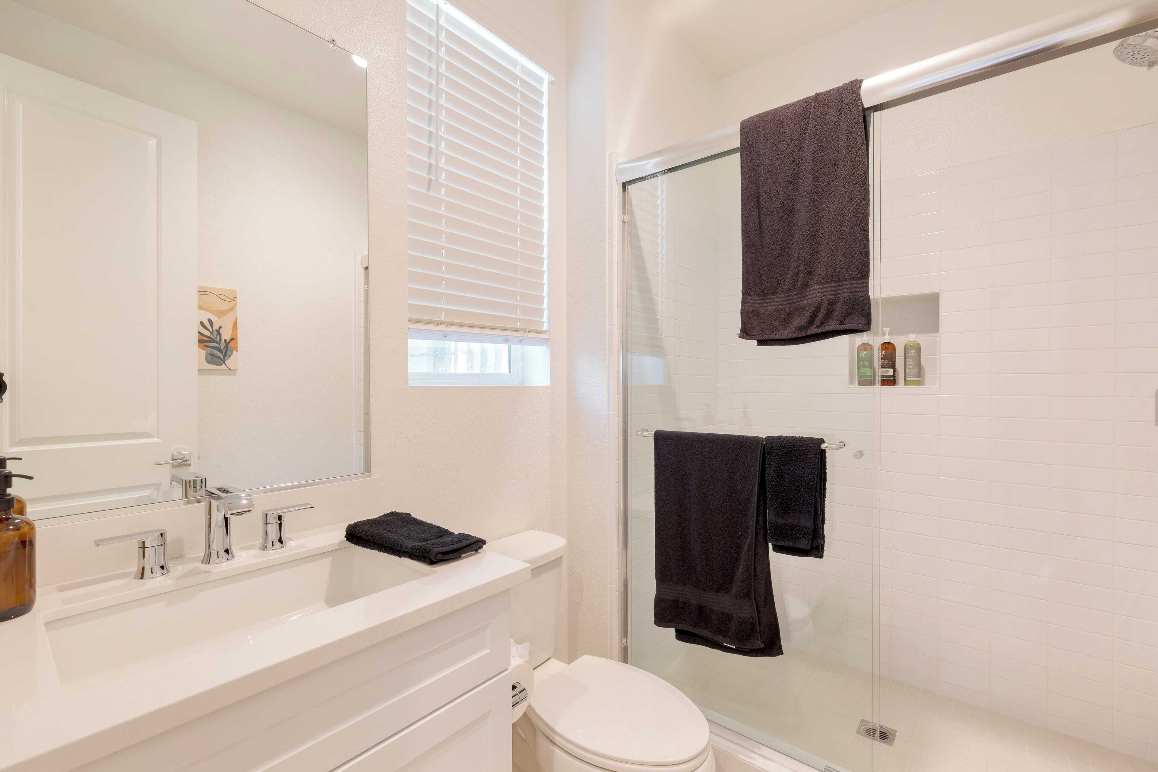 A bathroom with a white sink, mirror, and glass shower enclosure.