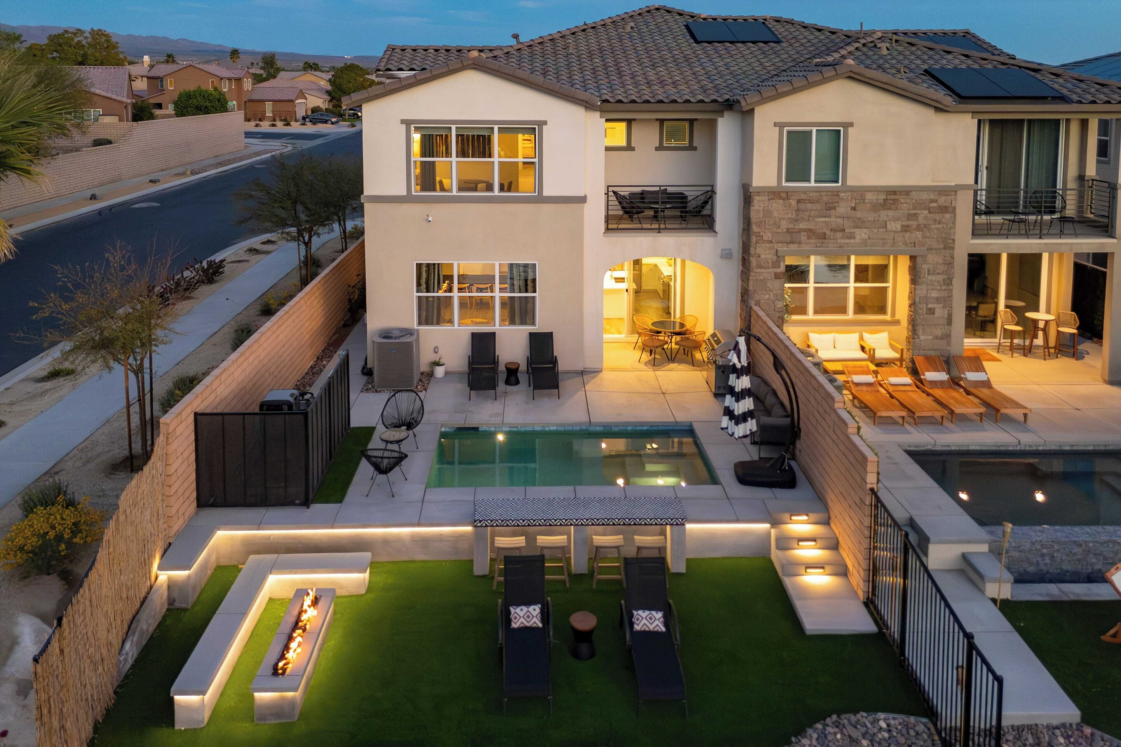 Une maison moderne à deux étages, dotée d’une piscine, d’un espace extérieur aménagé et d’un patio bien éclairé.
