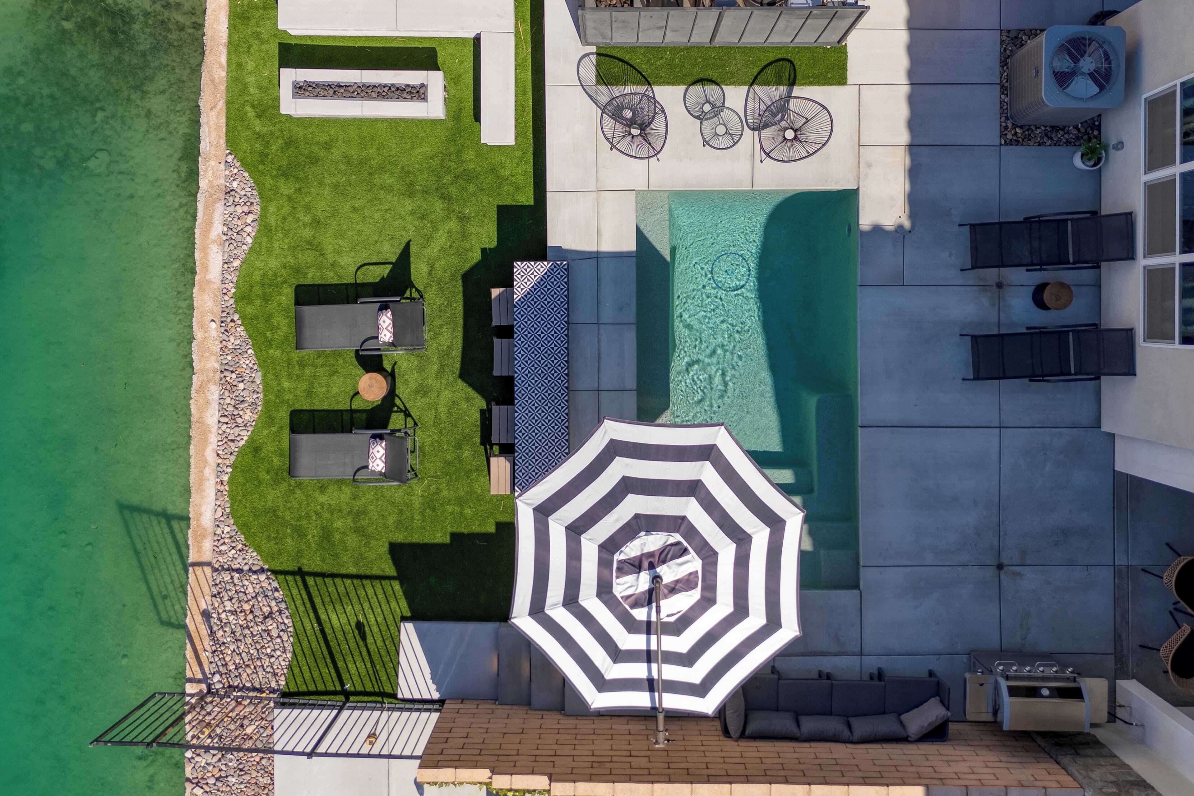 An aerial view of a backyard with a swimming pool, outdoor seating, and a barbecue area.