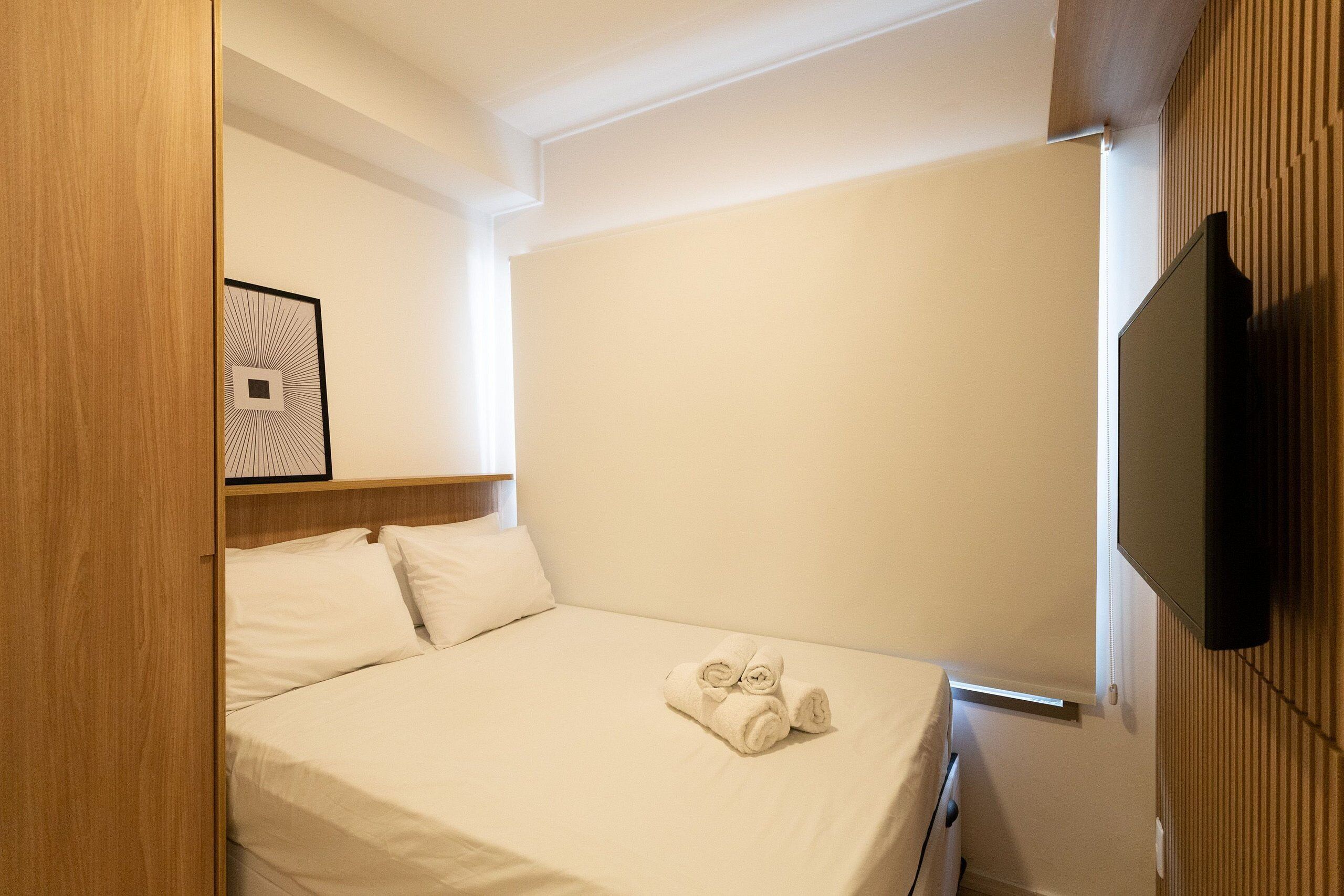 Ein Hotelzimmer mit einem Bett, einem Fernseher und einem gerahmten Bild an der Wand.
