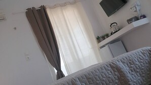 A bedroom with a bed, a ceiling light, a TV, and a small desk with a hairdryer. - Room in Guest Room - 12 Senses Faliraki Deluxe Room Near Sea 1 (Rhodes)