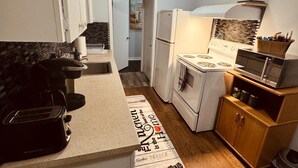A compact kitchen with a refrigerator, stove, microwave, and a toaster.