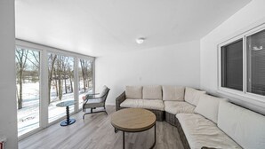 A modern living room with a large sectional sofa, a round coffee table, and a dining table.