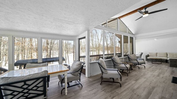 A spacious room with a long table and multiple chairs, large windows, and a ceiling fan.
