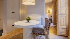 A modern hotel room with a round white table, a woven chair, a hanging light fixture, and a wooden wardrobe. - Rio by Wynwood House (Madrid)