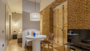 A modern living room with a brick wall, a round white table, a TV, and a fireplace. - Rio by Wynwood House (Madrid)