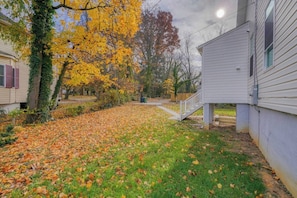 A residential area with a grassy yard, a wooden deck, and a white building with a porch.