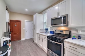 A modern kitchen with white cabinetry, a stainless steel microwave, and a gas stove.