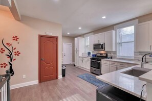 A kitchen with white cabinets, a microwave, an oven, and a sink.