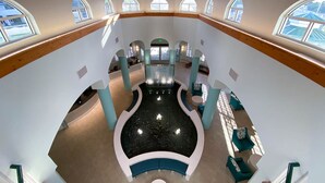 A spacious atrium with a central fountain, multiple seating areas, and large windows allowing natural light. - Cocoa Beach 2 BR 2 Bath Condo Ocean View & Balcony (Cocoa Beach)