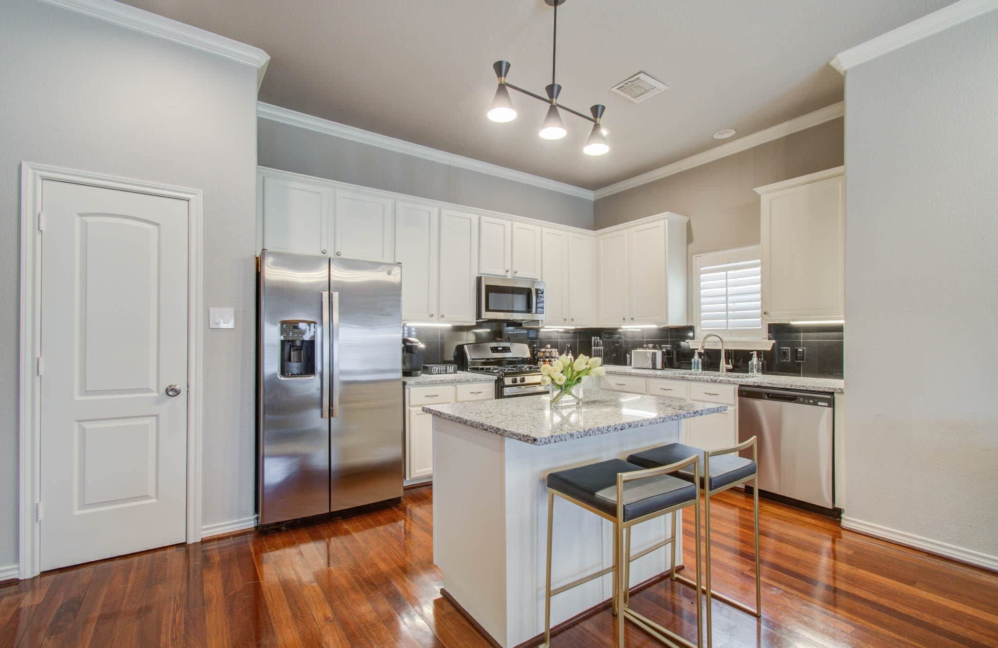 A modern kitchen with a stainless steel refrigerator, a built-in microwave, and a coffee bar.