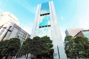 A tall, modern skyscraper with a glass facade, surrounded by trees and other buildings. - Toshi Center Hotel Tokyo (Tokyo)