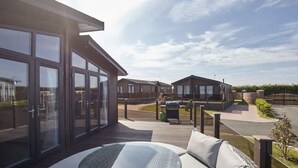 Une maison de vacances moderne dotée d’une grande terrasse, d’un espace barbecue et offrant une vue sur les maisons voisines.