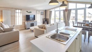 Une cuisine moderne avec un îlot central, un coin repas avec une table et des chaises, un canapé et un téléviseur dans le salon.
