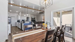A spacious kitchen with modern appliances, a dining area with a wooden table and chairs, and a large sliding glass door leading to an outdoor area. - Entire Home + Private Guest House in Caldwell, Idaho – Sleeps 20 (Caldwell)