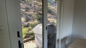 Et værelse med en skydedør, der fører ud til et udendørs område med en overdækket grill.