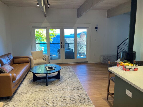 A spacious living room with a leather sofa, a coffee table, and a view of the ocean through large sliding glass doors.