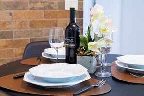 A table set with white plates, a wine bottle, a glass, and an orchid arrangement. - Apt no Butantã com 3 Quartos e 2 vagas (São Paulo)