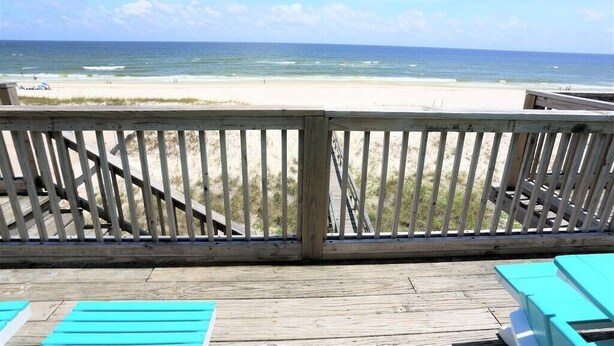 A wooden deck with a view of the beach and ocean.