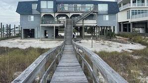 A beachfront building with a wooden boardwalk leading to the entrance.