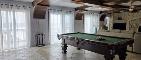 A spacious room with a pool table, a sofa, and a fireplace.