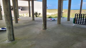 A covered outdoor area with concrete flooring, wooden pillars, and a view of the beach. - Boardwalk #3: Beachfront + Free Daily Admissions | Pet Friendly (Pensacola)