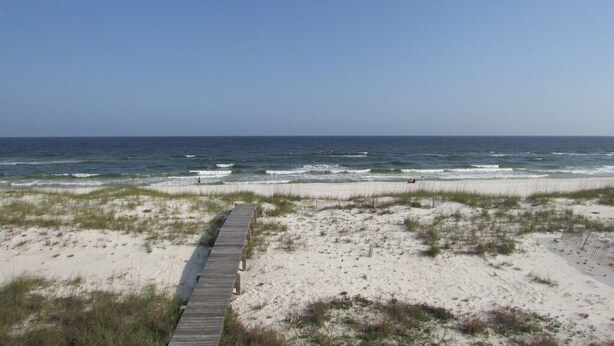 A beach with a wooden boardwalk leading to the water. - Boardwalk #3: Beachfront + Free Daily Admissions | Pet Friendly (Pensacola)