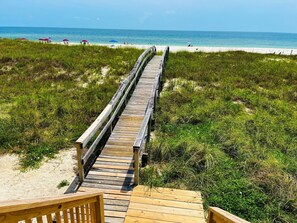 A wooden boardwalk leading to a beach with clear skies.