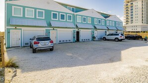 A two-story building with a light blue exterior and white trim. There are two garages and a covered parking area. - Dory A: Pet-Friendly Beachfront Townhome (3BR/2BA) (Pensacola)