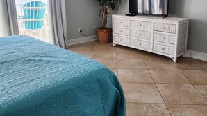 A bedroom with a bed, a ceiling fan, a TV, a plant, and a view of the outside. - Dory A: Pet-Friendly Beachfront Townhome (3BR/2BA) (Pensacola)