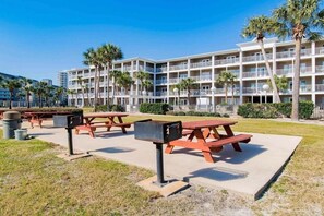 A hotel with multiple balconies, outdoor picnic tables, and palm trees. - Grand Caribbean 214W: Perdido Key 1BR: Ocean View, Pool, Hot Tub (Pensacola)