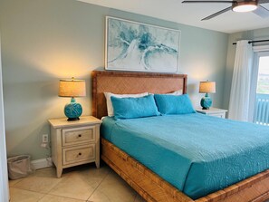 A bedroom with a bed, nightstands, a ceiling fan, and a window with curtains.