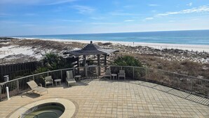 Une terrasse au bord de la plage, dotée d’une piscine, de chaises longues et d’un belvédère offrant une vue sur l’océan.